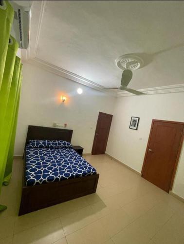 - une chambre avec un lit et un ventilateur de plafond dans l'établissement AGIM-GUESTHOUSSE, à Abomey-Calavi