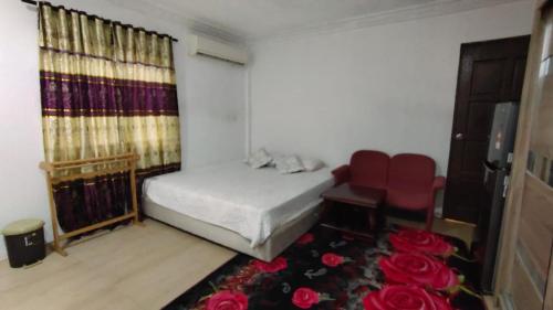 1 dormitorio con 1 cama, 1 silla y rosas en Raniah homestay en Kuching