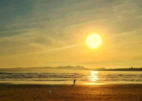 a person walking on the beach at sunset at Raniah homestay in Kuching