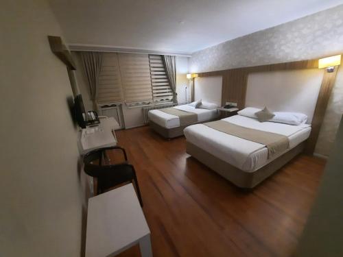 Cette chambre comprend 2 lits et une table. dans l'établissement PİTHANA OTEL, à Çorum