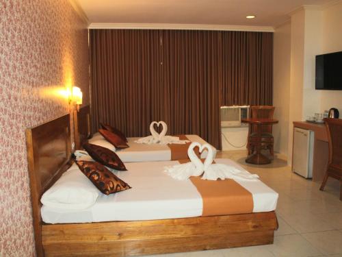 - 2 lits dans une chambre d'hôtel avec des cygnes dans l'établissement Rosas Garden Hotel, à Manille