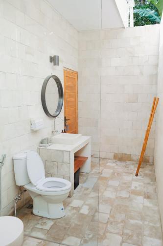 a bathroom with a toilet and a sink and a mirror at The Volter Yogyakarta in Ngingas