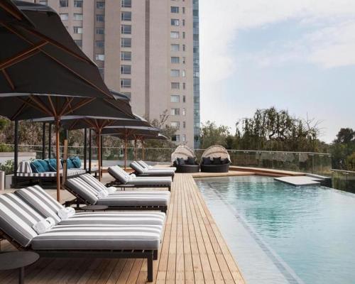 a row of lounge chairs and umbrellas next to a swimming pool at 1 Bedroom Luxury Apartment in Luxury Hotel & Apartments in Sandton Central in Johannesburg