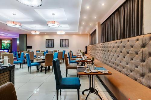 a dining room with tables and blue chairs at Protea Hotel by Marriott Lusaka in Lusaka