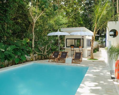 a swimming pool with two chairs and an umbrella at The Volter Yogyakarta in Ngingas