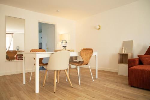 une salle à manger avec une table et des chaises blanches dans l'établissement Le Rozé - Appart'Escale, à Saint-Nazaire