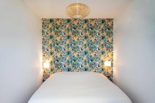 ein Schlafzimmer mit einem Bett mit einer tropischen Tapete in der Unterkunft Le Rozé - Appart'Escale in Saint-Nazaire