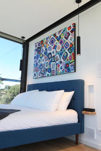 Un dormitorio con una cama azul con una pintura encima. en Avion Retreat en Pumpenbill