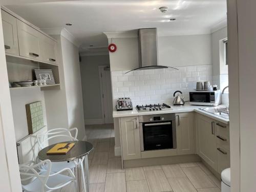 a kitchen with white appliances and a table and chairs at Beautiful Seafront Studio Apartment in Cleethorpes