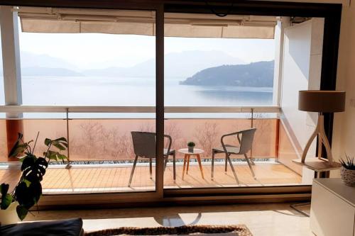 a room with a large window with chairs and a table at LE SOLAVUE 150 M2 VUE EXCEPTIONNELLE SUR LE LAC in Annecy