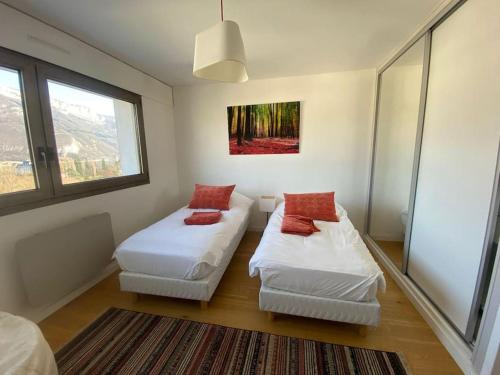 安锡LE SOLAVUE 150 M2 VUE EXCEPTIONNELLE SUR LE LAC的客房设有2张白色的床和窗户。