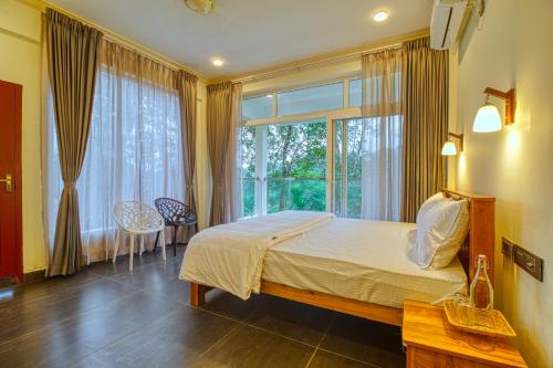 a bedroom with a bed and a large window at Ende Wayanad Resort in Koroth