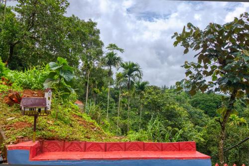 a red bench in front of a hill with trees at Ende Wayanad Resort in Koroth