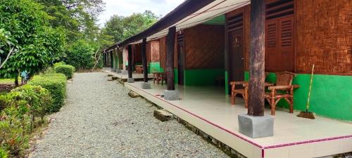 una casa con un camino al lado con sillas en el porche en Green Lodge Tangkahan en Tangkahan