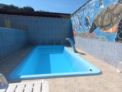 a blue swimming pool with a turtle mural on a wall at Casa Ubatuba Com Piscina in Ubatuba