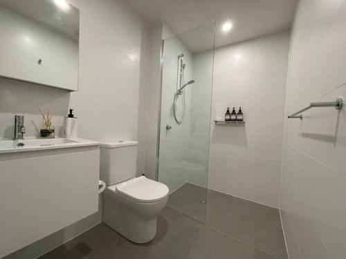 a white bathroom with a toilet and a shower at Brand new 1BR apartment Dickson in Canberra
