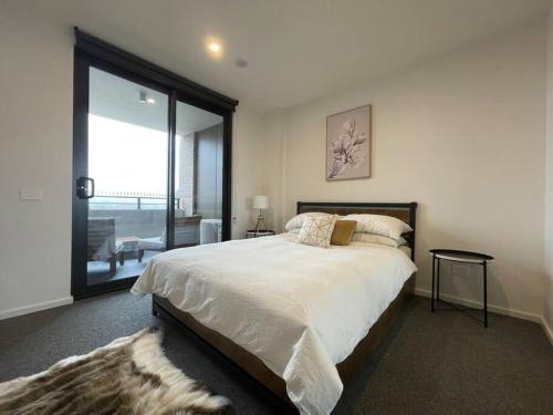 1 dormitorio con cama grande y ventana grande en Brand new 1BR apartment Dickson, en Canberra