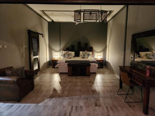 a bedroom with a bed and a couch and a piano at Mababe River Lodge in Mababe