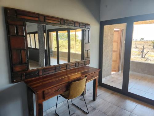 einen Schreibtisch mit einem Spiegel und einem Stuhl in einem Zimmer in der Unterkunft Mababe River Lodge & Campsite in Mababe