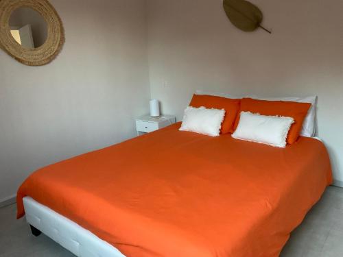 - une chambre avec un lit orange et 2 oreillers dans l'établissement COLORS by Reine du Sud, proche des Grands Buffets, à Narbonne