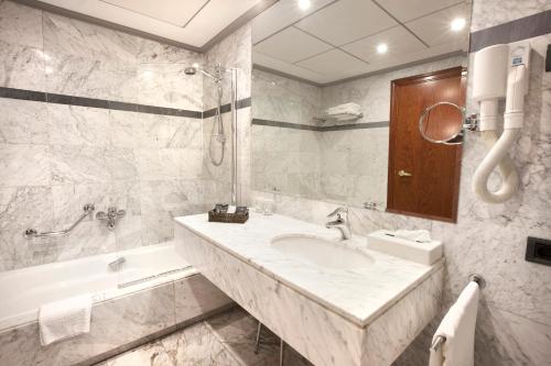 a bathroom with a sink and a tub and a mirror at Hotel Gran Via in Logroño