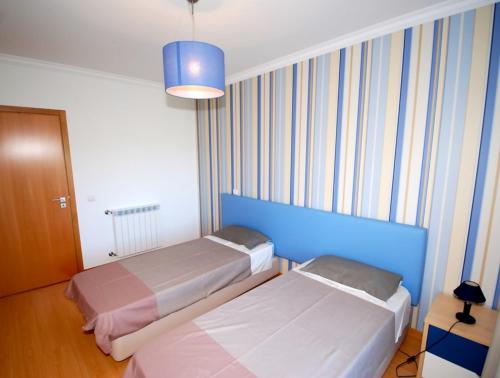 a bedroom with two beds and a blue wall at Alojamento Turistico in Maceira