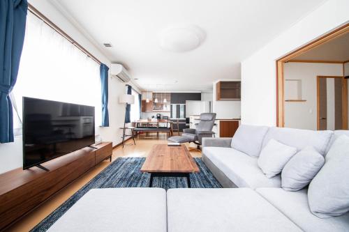 un soggiorno con divano bianco e tavolo di THE VILLA FURANO【Wide Horizon】 a Furano