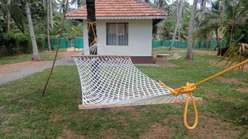 a hammock in the grass in front of a house at Prakruthi Residency Munroeisland in Munroe Island