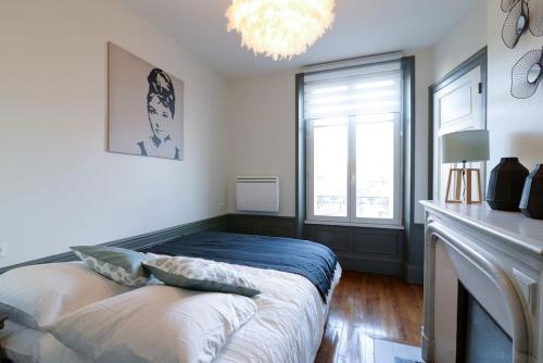 - une chambre avec un lit, une cheminée et un lustre dans l'établissement Le Grand Serre - Triangle d'or nancéien, à Nancy