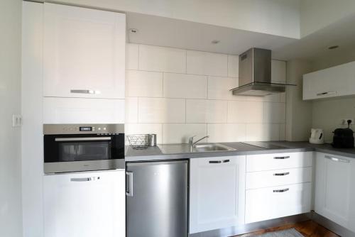 une cuisine avec des armoires blanches et un appareil en acier inoxydable dans l'établissement Le Grand Serre - Triangle d'or nancéien, à Nancy