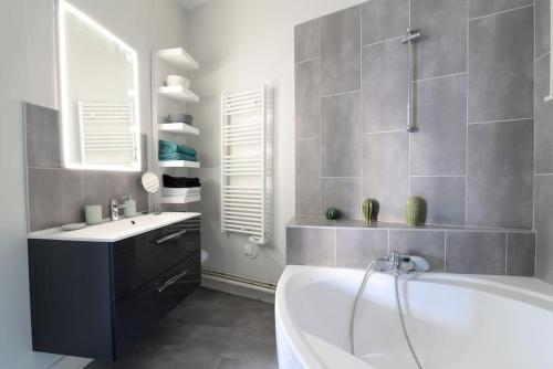 une salle de bain avec une baignoire blanche et un lavabo dans l'établissement Le Grand Serre - Triangle d'or nancéien, à Nancy