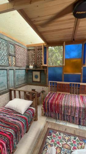 a room with two beds and a table and windows at Maison Nassimah in Giza