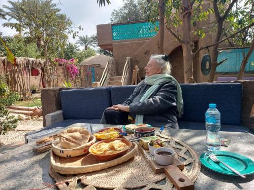 un hombre sentado en un sofá con una bandeja de comida en Nassimah, en Giza