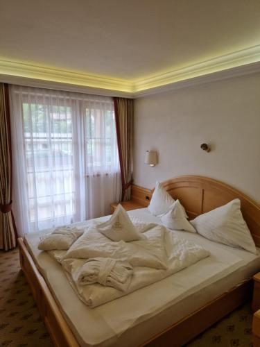 a bedroom with a bed with white sheets and a window at Residence Ciastel in Ortisei