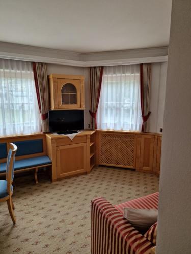 a living room with a couch and a tv and windows at Residence Ciastel in Ortisei