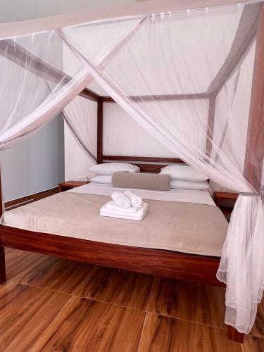 a bedroom with a bed with a mosquito net at S&S HOTEL in Jambiani