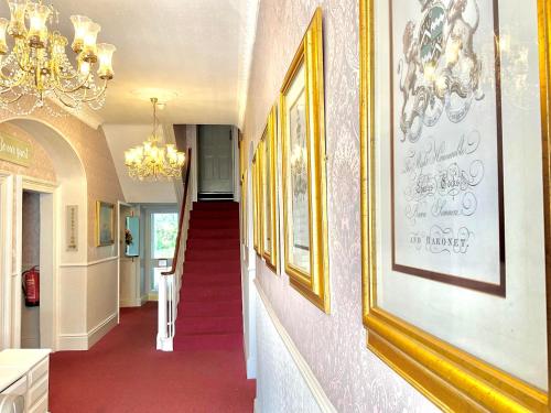 a hallway with a red carpet and pictures on the wall at Ashton Court Hotel in Exmouth