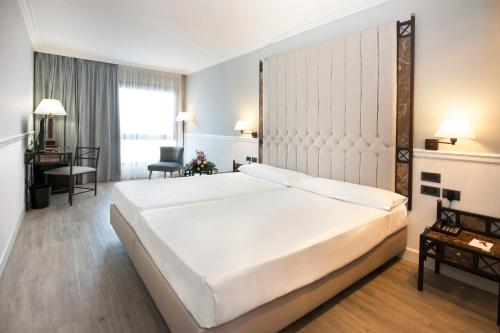 a bedroom with a large white bed in a room at Hotel Gran Via in Logroño
