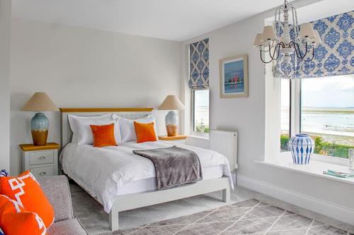 Seafront Apartment with Stunning Views في كْليثوربس: غرفة نوم مع سرير مع وسائد برتقالية ونافذة