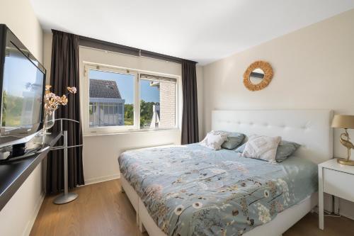 a bedroom with a bed and a tv and a window at Luxury Apartment near Utrecht & Amsterdam in Breukelen