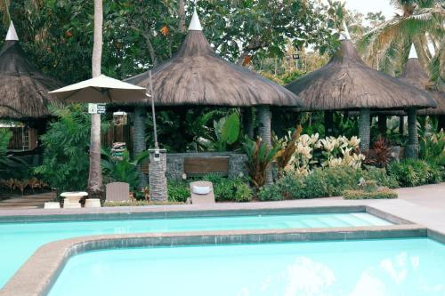 a swimming pool in front of a resort with an umbrella at Maria Aliyah Events and Resort in Santa Cruz