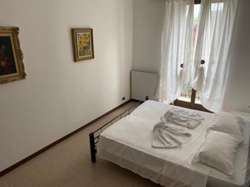 ein weißes Bett in einem Zimmer mit Fenster in der Unterkunft HOTEL RISTORANTE VITTORIA dal 1920 in Marzio