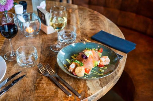 a wooden table with a plate of food and glasses of wine at Luxury Apartment near Utrecht & Amsterdam in Breukelen