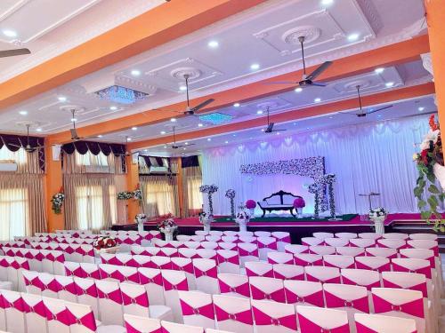 a banquet hall with red and white chairs and a grand piano at Hotel Juli Reception in Mannar