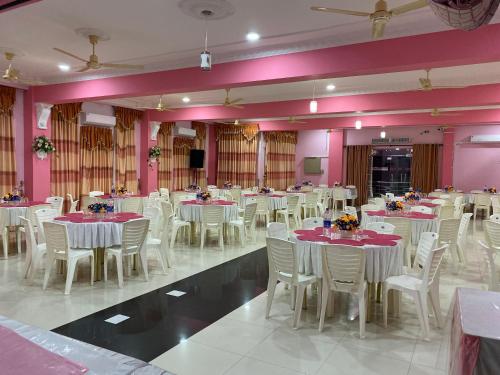 um salão de banquetes com mesas e cadeiras brancas e paredes cor-de-rosa em Hotel Juli Reception em Manar