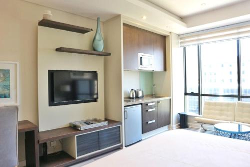 a living room with a television and a kitchen at Sandton Skye Apartments in Johannesburg