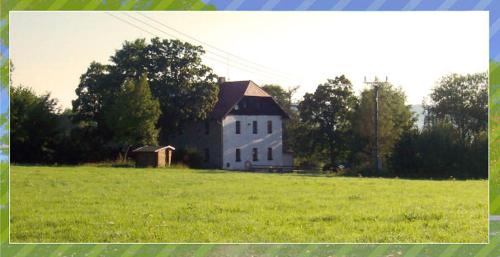 a large white house in a field of green grass at Penzion Vozzýk in Nové Hutě