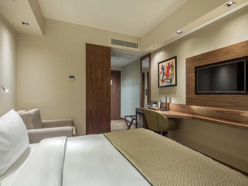 a hotel room with a bed and a flat screen tv at Holiday Inn Antalya - Lara by IHG in Antalya