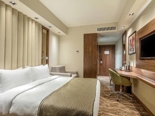 a hotel room with a bed and a desk at Holiday Inn Antalya - Lara by IHG in Antalya
