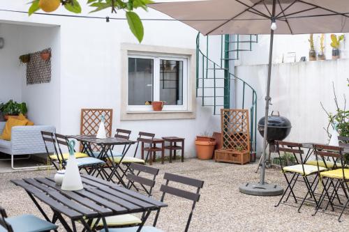 an outdoor patio with tables and chairs and an umbrella at Ó da Casa in Peniche